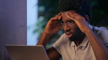 Overworked stressed businessman African American business man in office problem laptop working online mistake failure upset trouble computer overtime night evening job disappointed sad tired employer video