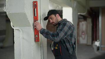 Man builder engineer repairman measuring wall with bubble level tool building apartment renovation male guy electrician inspector foreman industry architect measure inspect construction think solution video