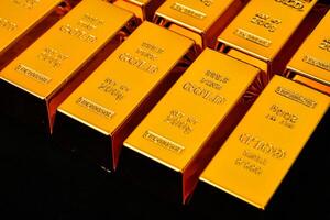 gold bars are stacked in rows on a black surface photo