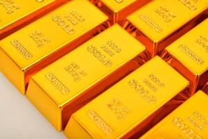 gold bars are stacked in rows on a white surface photo