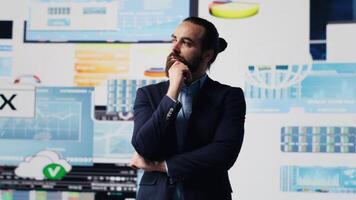 Businessman thinking about a new solution to increase funding while he evaluates infographics and financial reports with digital technology. Planning long term success and growth. Camera A. video