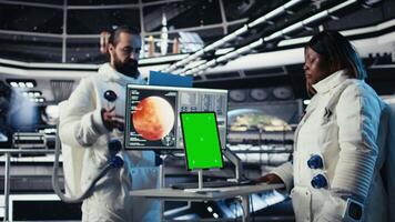 Astronauts reviewing onboard analytics on isolated screen tablet before stepping outside starship. Cosmonauts verifying parameters on chroma key device after landing on planet, camera A video