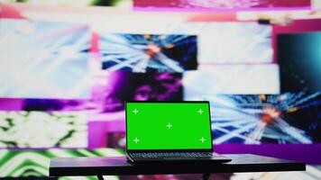 Wireless pc running chroma key display surrounded by colorful visual art clips, glowing in the dark and showcasing a clubbing atmosphere. Nightlife ambiance with urban lights and vibes. Camera B. video