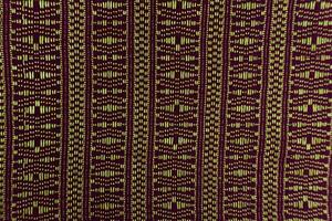 A textured fabric swatch displays vertical stripes of detailed geometric patterns in dark and light shades, revealing the fine craftsmanship of textile weaving. photo