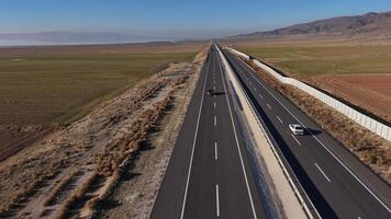 Aerial. vehicle drives down a highway with green fields stretching endlessly video