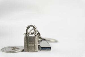 A padlock, coin, and USB flash drive lie on a white surface, symbolizing data security and storage. photo