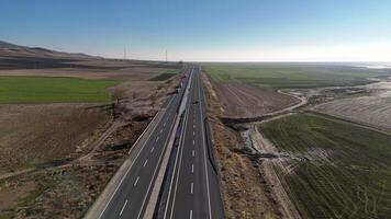 Aerial. car drives along a modern highway surrounded by open green fields. video