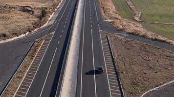 An aerial view of a car on a quiet highway bordered by green fields video