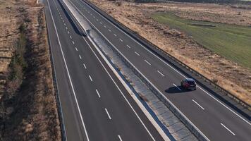 Captured from above, a red car travels on a highway surrounded by fields video