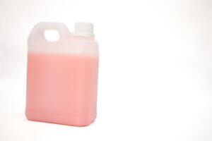 A plastic gallon container filled with pink liquid sits on a white background ready for use photo