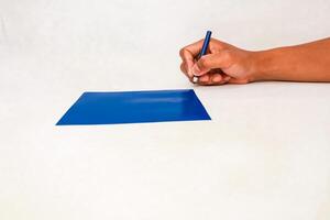 Writing on a blue surface with a pencil on a white background with human hand photo