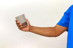 A man in a blue shirt holds a disposable cup with a striped pattern against a white background photo