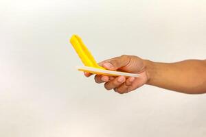 Close-up of a hand holding a yellow squeegee against a plain white background showcasing cleaning equipment photo