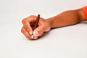 Close-up of a hand writing or drawing with a colored pencil on a white surface photo