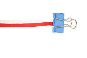 A blue binder clip holding a red and white ribbon on a white background photo