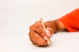 Close-up of a dark-skinned hand holding a pencil, creating, drawing or writing on a clean white surface photo