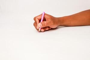 A dark-skinned hand holds a pink pencil, poised to write or draw on blank paper with space photo
