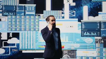 Professional businessman answering a phone call surrounded by KPI metrics to evaluate company performance and insight. Using remote communication to improve his business, greatness. Camera B. video