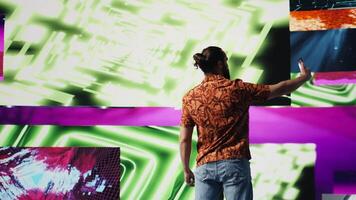 Young carefree man takes selfies and videos surrounded by fun neon lights and beats, representing the fusion of modern DJ culture, media influence and digital art for performance. Camera B.
