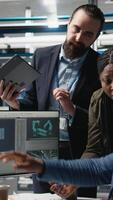 Vertical Group of professional consultants reviewing data and checklists in a high tech solar panel plant, ensuring manufacturing process meets sustainable energy and innovation standards. Camera A. video