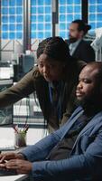 Vertical African american team of engineers collaborating in a solar energy facility, reviewing blueprints and performance metrics to enhance sustainable alternative energy and manufacturing. Camera A. video