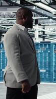 Vertical Happy businessman walking in data center, assessing rackmounts capacity before investing. Jolly management executive overseeing server farm built for business storage gear, camera A video