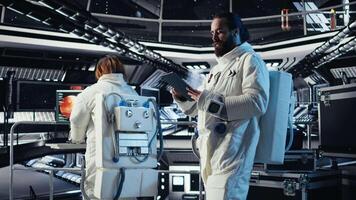 Cosmonaut using tablet in spaceship conducting safety checks during mankind survival expedition. Astronauts monitoring life support systems during human expansion in space mission, camera A video