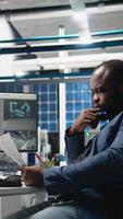 Vertical African american business engineer reviewing solar cell factory operations, handling the manufacturing process for photovoltaics industry. Expert working in modern plant. Camera A. video