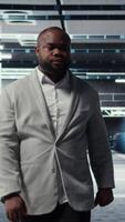 Vertical Smiling employee walking in high tech data center with machines powering networks, running companies databases. Admin overseeing server farm with rigs modules processing large datasets, camera A video