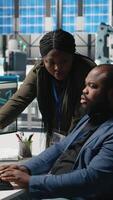 Vertical African american factory experts engaging in manufacturing process analysis, reviewing industrial operations for the production line. Solar power high tech development. Camera A. video