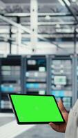 Vertical Engineer in data center using green screen tablet to develop disaster recovery plans. IT expert in server farm testing failover scenarios on mockup device, protecting data during disruptions, camera A video