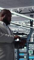 Vertical Smiling data center technician installing and upgrading hardware components. Happy server farm employee doing job tasks, implementing backup solutions to protect against data loss, camera A video