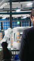 Vertical Professional engineer managing the production line for solar panels, examining equipment and efficiency in the modern factory. Businessman expert works on alternative energy. Camera A. video