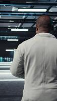 Vertical Technician using laptop in data center, managing server virtualization, running scripts. IT expert using programming language on notebook in server hub, finetuning network protocols, camera A video