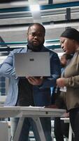 Vertical African American industrial coworkers doing teamwork on production line for solar panels, combining technical insight and teamwork to drive forward clean energy infrastructure. Camera A. video