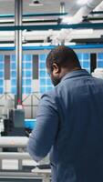 Vertical African american industry expert reviewing photovoltaics assembly line, inspecting the production to ensure efficiency in the solar energy business. Young master engineer in a factory. Camera A. video