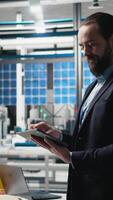 Vertical Industrial male expert in suit inspecting solar power equipment, demonstrating efficiency in quality control and production line. Working on solar panels manufacturing. Camera A. video