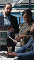 Vertical Multiethnic master engineers doing teamwork on high tech production line for solar panels manufacturing activity, combining technical insight and collaboration for green energy. Camera A. video