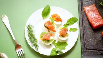Decorated eggs with red fish and greens on a table on a green background video