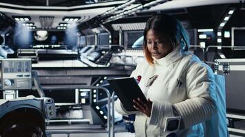 Female astronaut using tablet to check space station analytics after completing surface mission on unfamiliar planet. Woman inputting navigation coordinates, preparing for return to Earth, camera A video