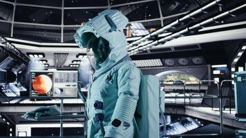 Female astronaut in spacesuit checks wrist device inside spacecraft doing human expansion in space. Starship crew member prepares for operations supporting long term mankind survival, camera A video