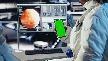 Astronaut using green screen smartphone to text friends before landing spaceship on Mars. Woman using chroma key phone to chat with family during mission to red planet surface in deep space, camera B video