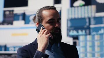 Professional businessman answering a phone call surrounded by KPI metrics to evaluate company performance and insight. Using remote communication to improve his business, greatness. Camera A. video