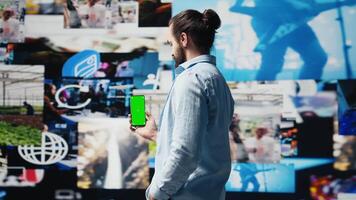Young adult holds phone with chroma key screen and connecting on socials, using his imagination and modern e commerce skills to connect with people online. Entertainment. Camera B. video