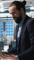 Vertical Facility supervisor in a suit monitoring solar panel assembly line, reflecting professional occupation and executive level involvement in renewable energy growth. Sustainability. Camera A. video