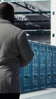 Vertical Admin walking in data center, doing inspection on infrastructure tech handling user requests. IT professional in server farm analyzing traffic patterns of equipment components, camera A video