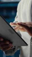 Vertical Close up of system administrator walking in data center, using tablet to check gear for system stability. IT specialist overseeing server hub, using device to configure rigs, optimizing performance video