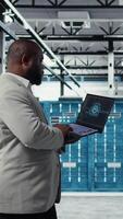 Vertical Data center admin doing IT maintenance tasks using AI technology. Server hub engineer providing tech support after identifying hardware issues using predictive artificial intelligence alerts, camera A video