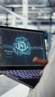 Vertical Close up of server hub admin using laptop to do infrastructure AI machine learning automatization. Data center programmer doing maintenance using artificial intelligence, camera A video