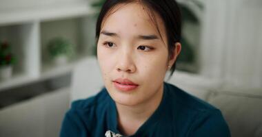 Handheld selective focus shot, Asian woman sitting alone on the sofa thinking about life problems with a stressed expression. video